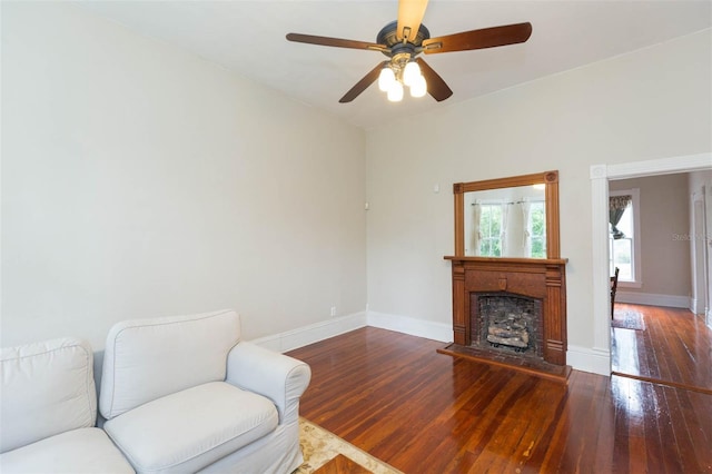 living area featuring hardwood / wood-style floors, ceiling fan, and baseboards