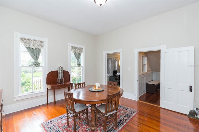 dining space with wood-type flooring and baseboards