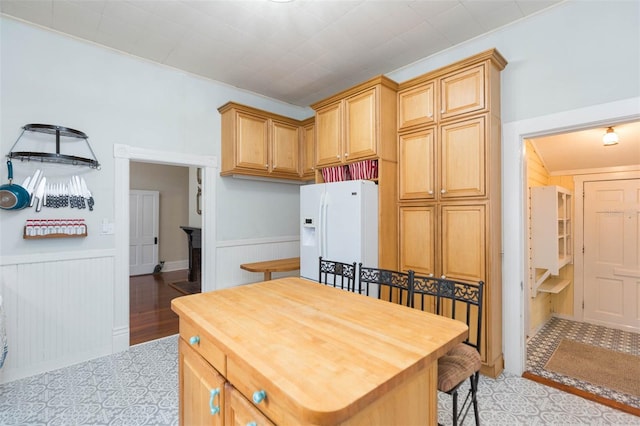 kitchen featuring wood counters, white fridge with ice dispenser, and wainscoting