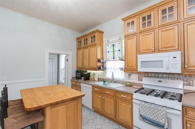 kitchen featuring white appliances, a breakfast bar, wood counters, a sink, and wainscoting