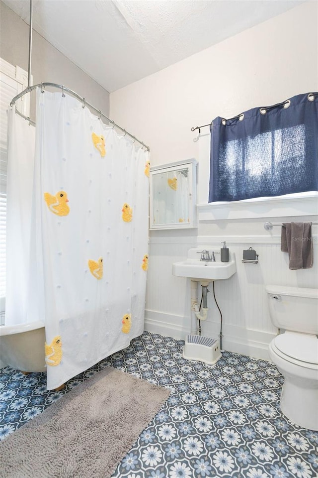 full bathroom featuring a shower with curtain, baseboards, toilet, and a sink