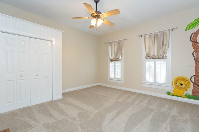 unfurnished bedroom featuring a ceiling fan, carpet, a closet, and baseboards