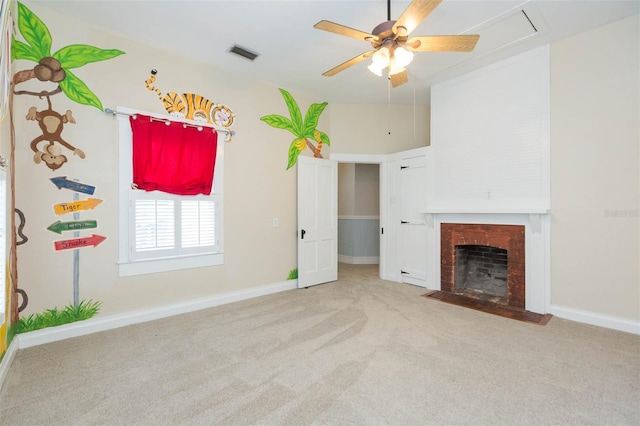 unfurnished living room featuring a fireplace with flush hearth, carpet flooring, visible vents, a ceiling fan, and attic access