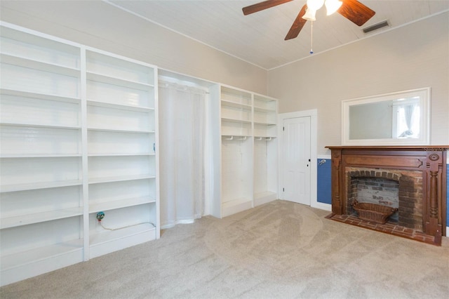 unfurnished living room with carpet floors, a fireplace, visible vents, and a ceiling fan