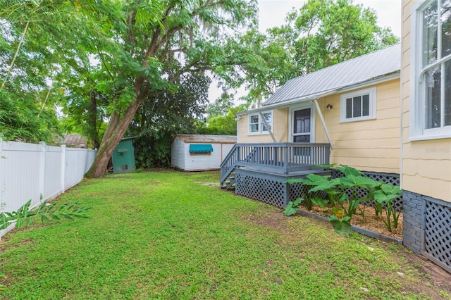view of yard featuring a shed, an outdoor structure, a deck, and fence