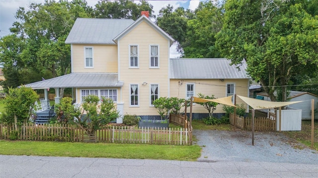 view of front of home featuring metal roof, a fenced front yard, and a chimney