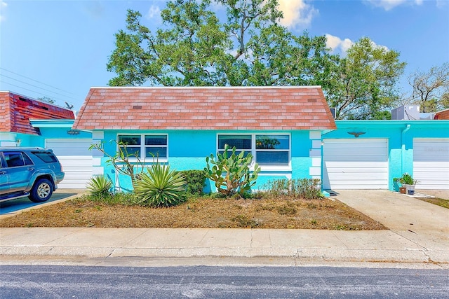 view of front facade featuring a garage, driveway, stucco siding, and a shingled roof