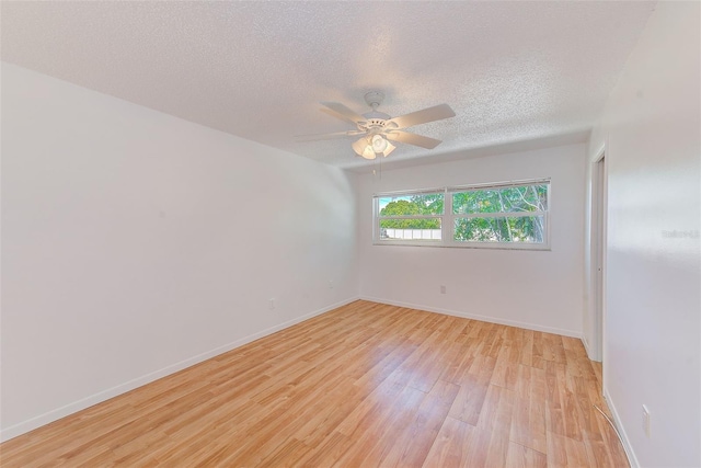 spare room with a ceiling fan, baseboards, light wood-style floors, and a textured ceiling