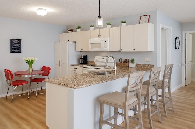 3533 Roanoke St, The Villages, FL 32162 - kitchen featuring white microwave, light wood-style floors, light stone countertops, a breakfast bar area, and electric range oven