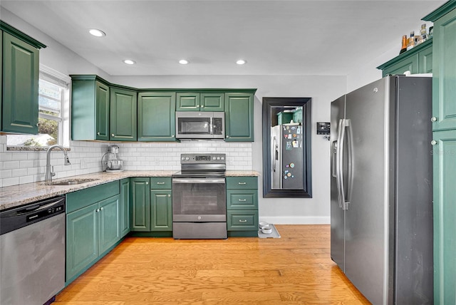 705 28th St N, Saint Petersburg, FL 33713 - kitchen featuring decorative backsplash, green cabinets, appliances with stainless steel finishes, a sink, and light wood-style floors