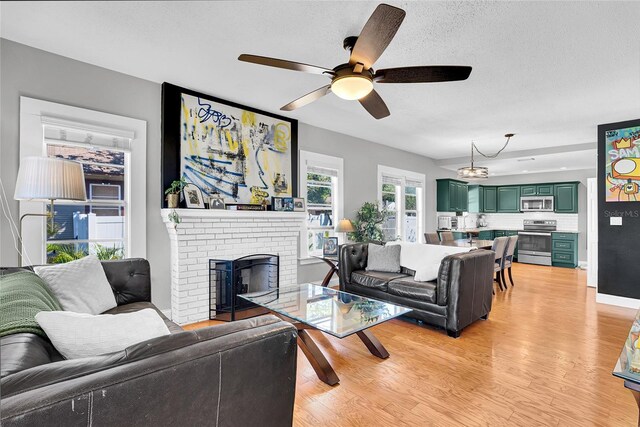 705 28th St N, Saint Petersburg, FL 33713 - living area featuring a ceiling fan, a textured ceiling, a fireplace, and light wood-type flooring