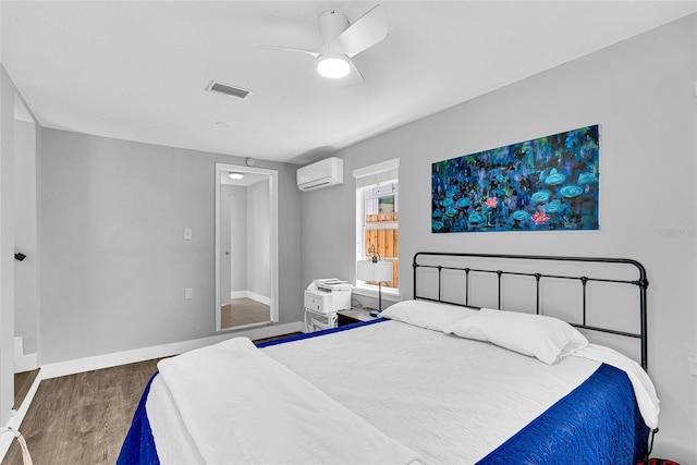 705 28th St N, Saint Petersburg, FL 33713 - bedroom with visible vents, baseboards, wood finished floors, a ceiling fan, and a wall unit AC