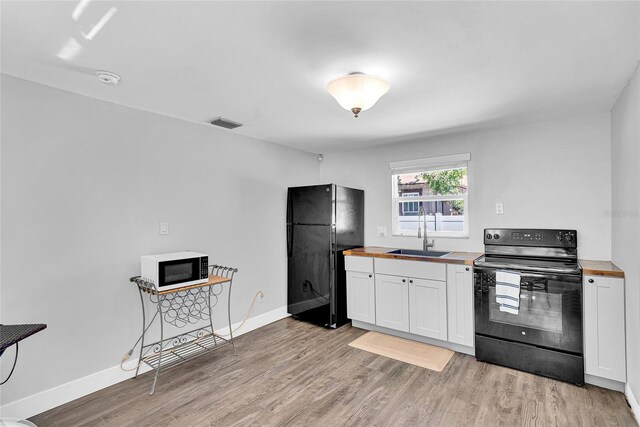 705 28th St N, Saint Petersburg, FL 33713 - kitchen with a sink, wood counters, black appliances, and light wood-type flooring