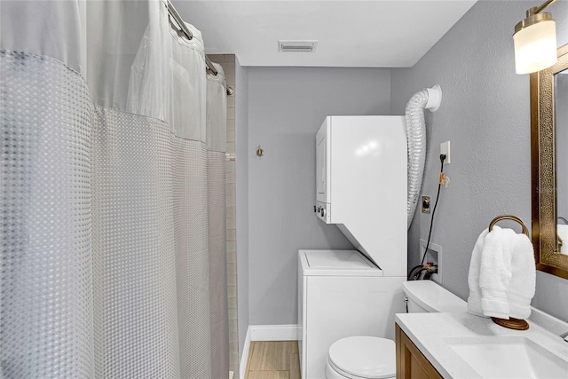 705 28th St N, Saint Petersburg, FL 33713 - full bathroom featuring toilet, vanity, wood finished floors, stacked washer and clothes dryer, and visible vents