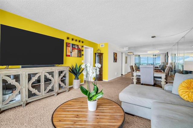 living area featuring carpet flooring, a textured ceiling, a chandelier, baseboards, and visible vents
