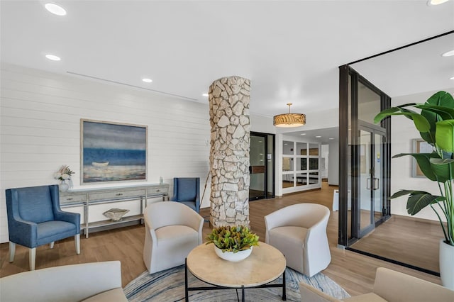 living area featuring ornate columns, recessed lighting, and wood finished floors