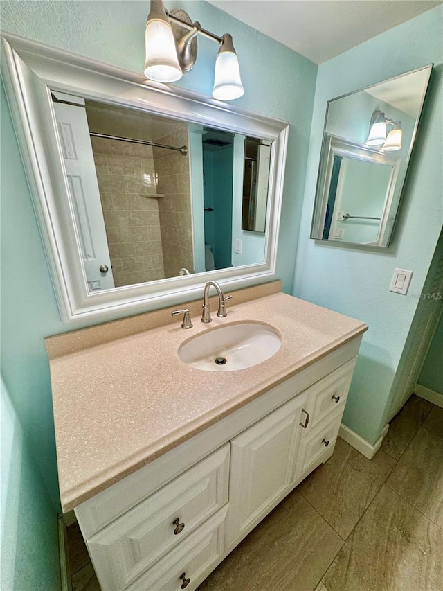 bathroom with vanity, tile patterned flooring, baseboards, and a shower