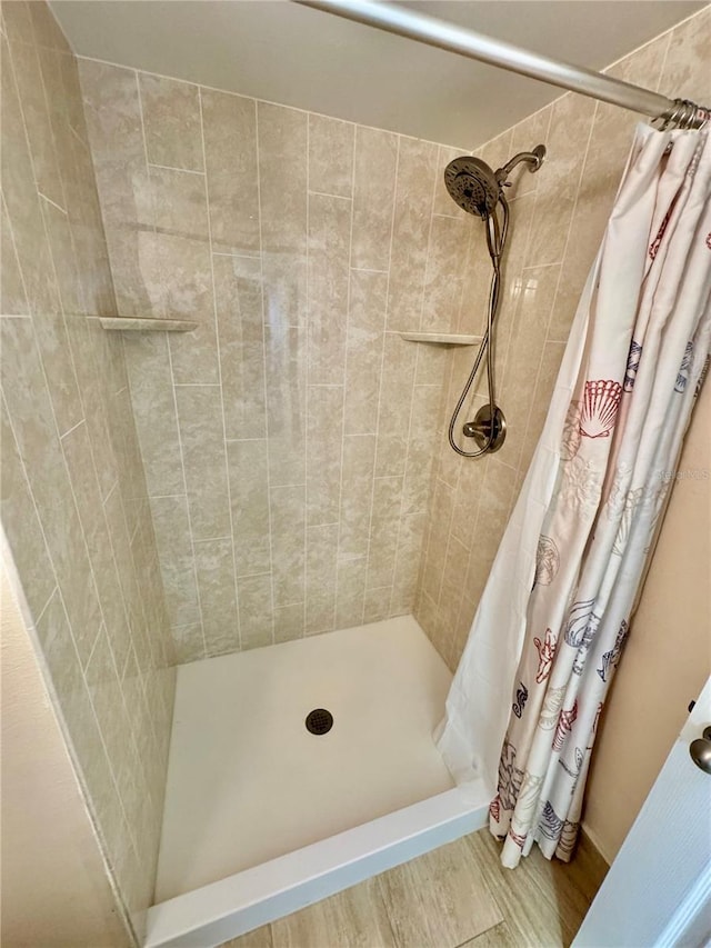 bathroom featuring wood finished floors and a stall shower