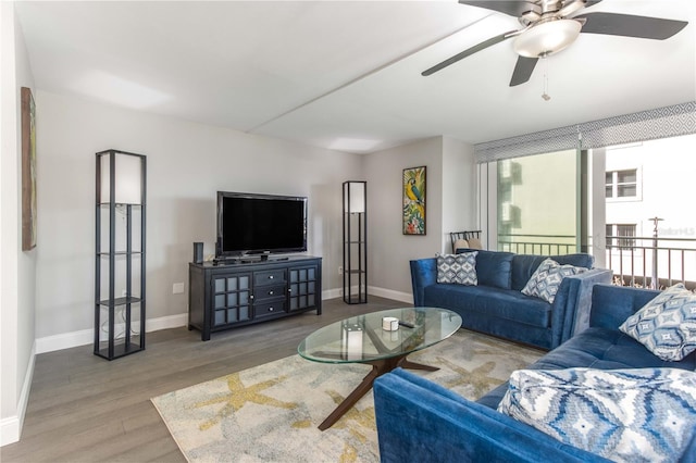 living room featuring baseboards, a ceiling fan, and wood finished floors