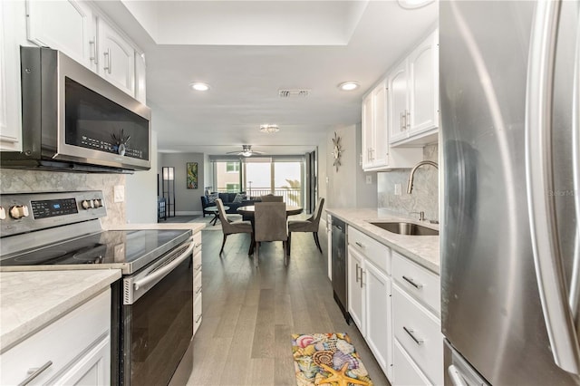 1390 Gulf Blvd Unit 104, Clearwater, FL 33767 - kitchen featuring appliances with stainless steel finishes, backsplash, light wood finished floors, white cabinets, and recessed lighting