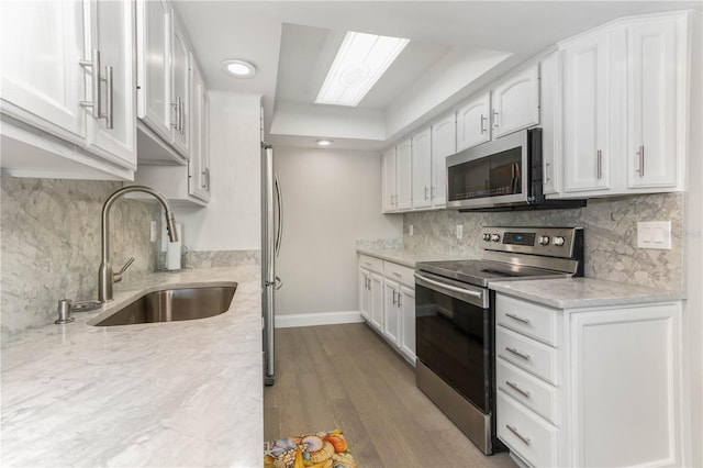 1390 Gulf Blvd Unit 104, Clearwater, FL 33767 - kitchen with stainless steel appliances, white cabinetry, tasteful backsplash, wood finished floors, and recessed lighting