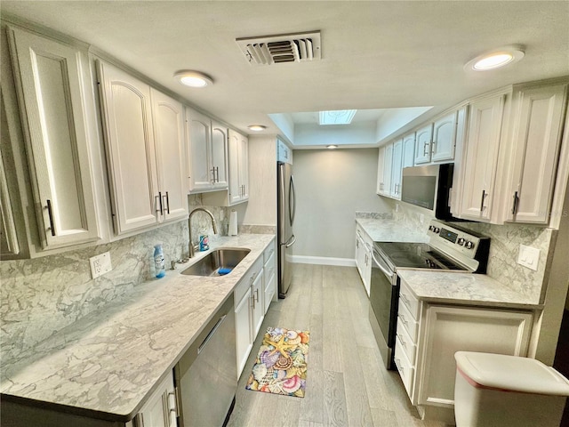 1390 Gulf Blvd Unit 104, Clearwater, FL 33767 - kitchen featuring appliances with stainless steel finishes, a skylight, light wood-style flooring, backsplash, and light countertops