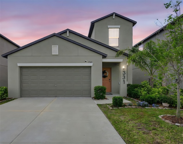 view of front facade featuring an attached garage, driveway, and stucco siding
