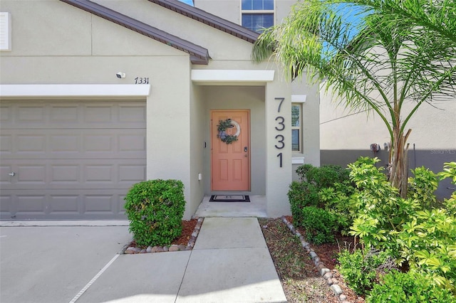 entrance to property with stucco siding and an attached garage