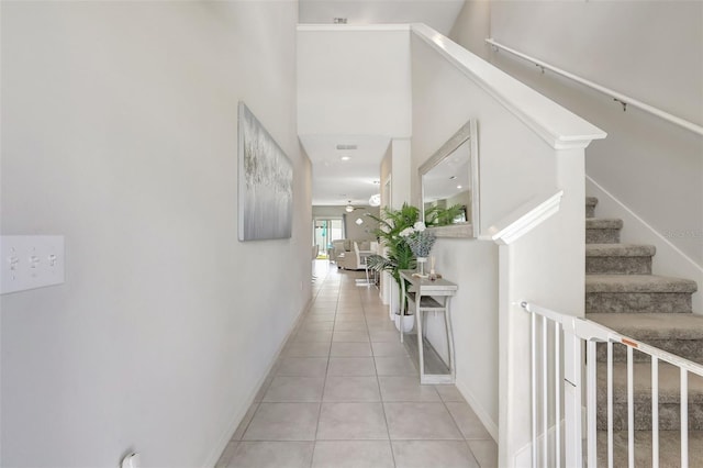 hall with light tile patterned floors, baseboards, and stairway