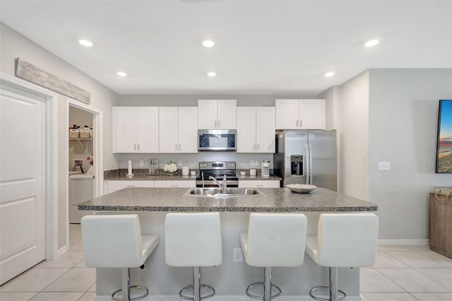 kitchen with a breakfast bar, light tile patterned floors, white cabinets, appliances with stainless steel finishes, and a sink