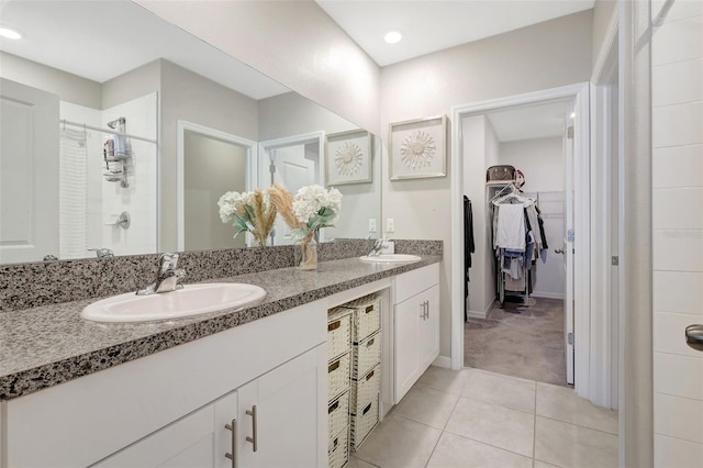 full bathroom with a sink, tile patterned floors, a tile shower, and a spacious closet