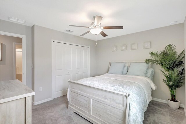 bedroom with visible vents, baseboards, a closet, and light colored carpet
