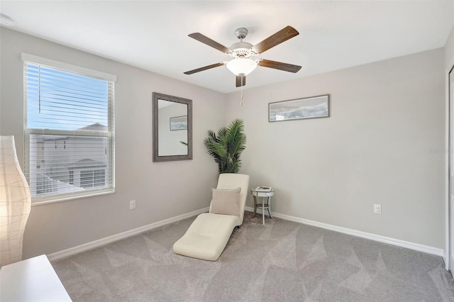 living area featuring baseboards, a ceiling fan, and carpet floors