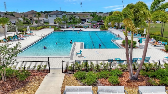 community pool featuring a residential view, a patio, and fence