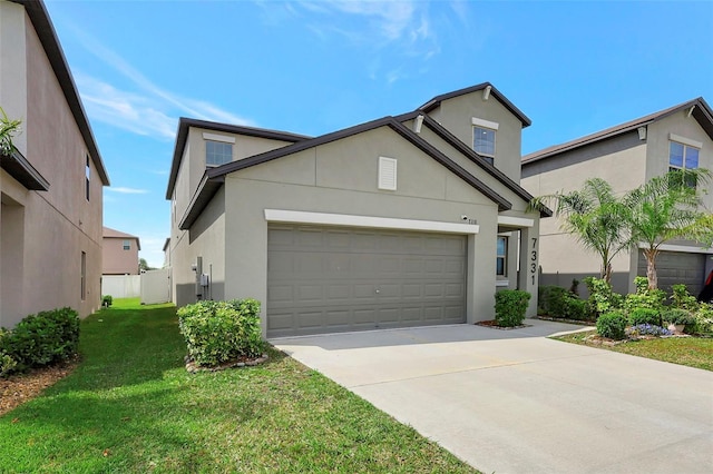view of front of property featuring a front lawn, an attached garage, driveway, and stucco siding