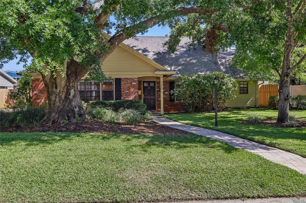 2809 Kimberly Ln, Tampa, FL 33618 - view of front of home with brick siding, a front lawn, fence, and a shingled roof