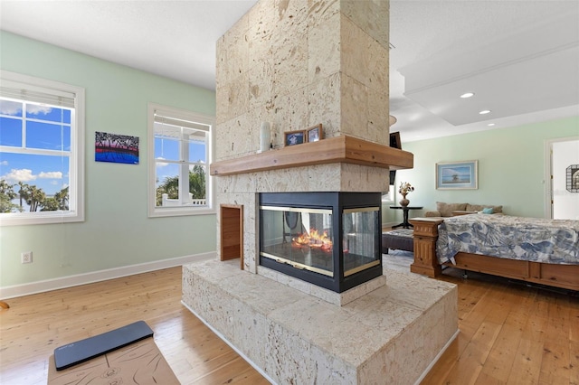 450 Bayshore Dr, Terra Ceia, FL 34250 - bedroom with baseboards, a multi sided fireplace, recessed lighting, and hardwood / wood-style flooring