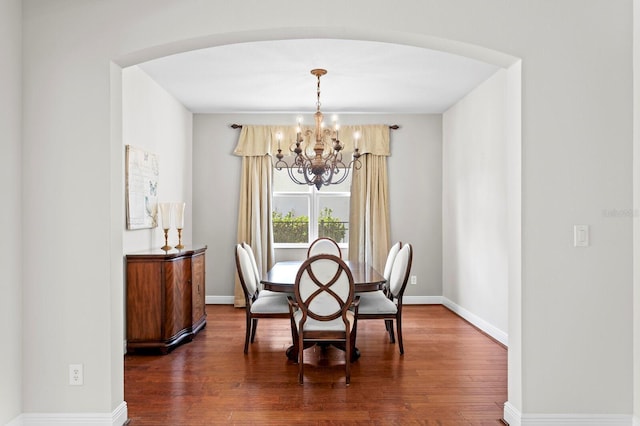 dining room with arched walkways, baseboards, a chandelier, and dark wood finished floors