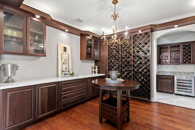 wine room with dark wood-type flooring, visible vents, indoor wet bar, and beverage cooler