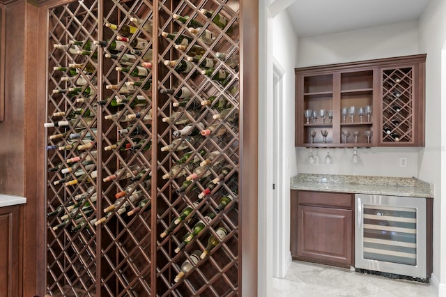 wine area with a dry bar, wine cooler, and marble finish floor