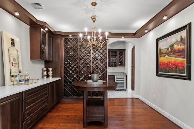 interior space with a bar, dark wood-style floors, visible vents, and wine cooler