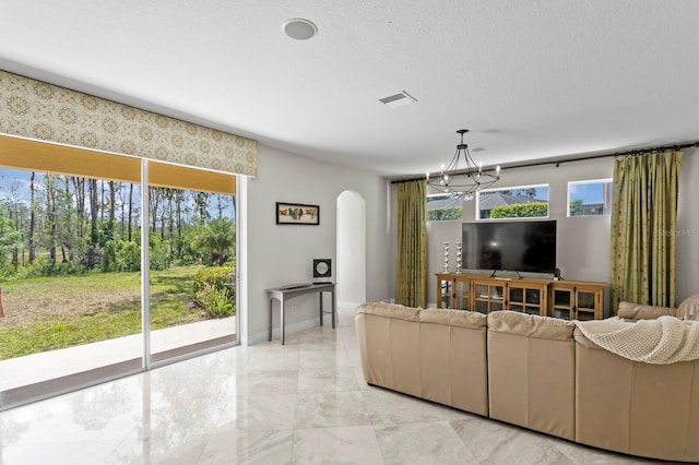 living room featuring a chandelier, a textured ceiling, marble finish floor, visible vents, and arched walkways