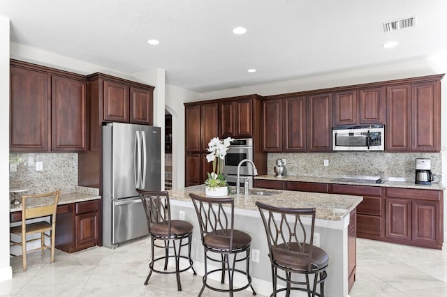 kitchen with a kitchen bar, arched walkways, a sink, and stainless steel appliances