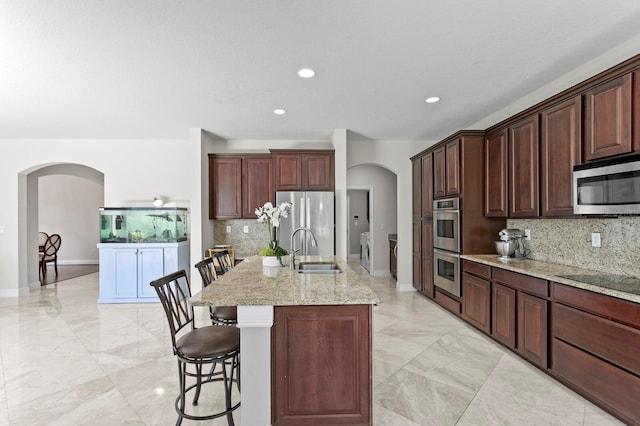 kitchen with arched walkways, marble finish floor, a sink, and stainless steel appliances