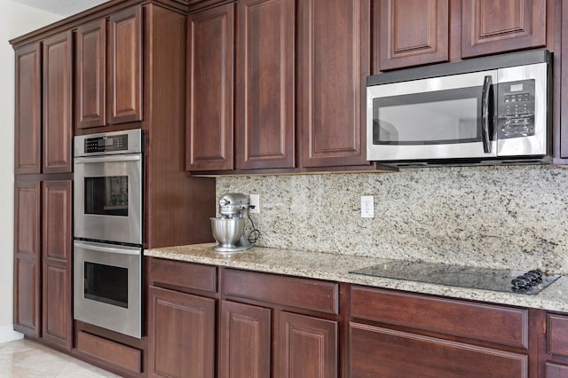 kitchen with light stone countertops, stainless steel appliances, and tasteful backsplash