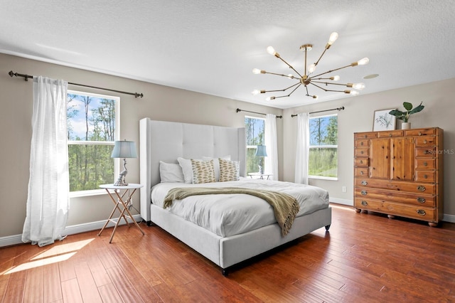 bedroom featuring baseboards, a textured ceiling, a chandelier, and hardwood / wood-style flooring