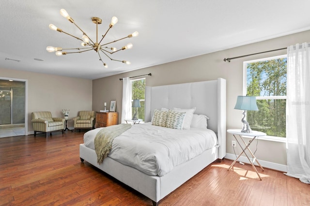 bedroom with wood-type flooring, baseboards, a chandelier, and visible vents