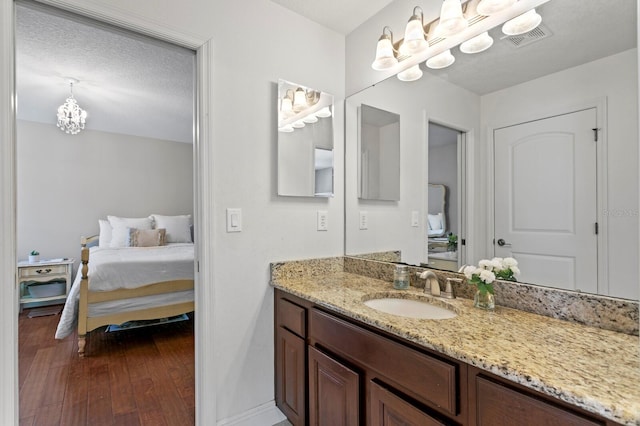 bathroom featuring vanity, a chandelier, wood finished floors, ensuite bath, and visible vents