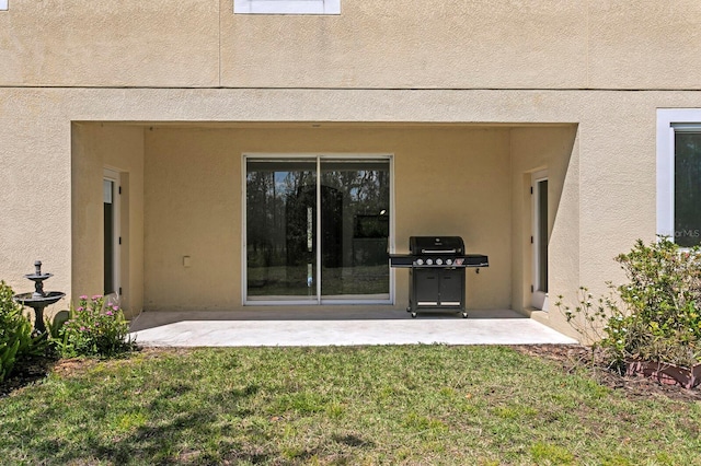 back of house with a lawn, stucco siding, and a patio