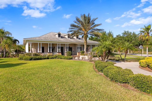back of house with stucco siding, covered porch, and a yard